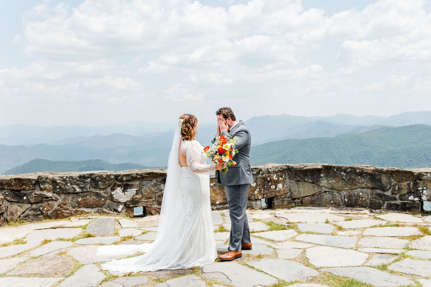 Couple sharing a romantic moment on a scenic mountain overlook with expansive valley views.