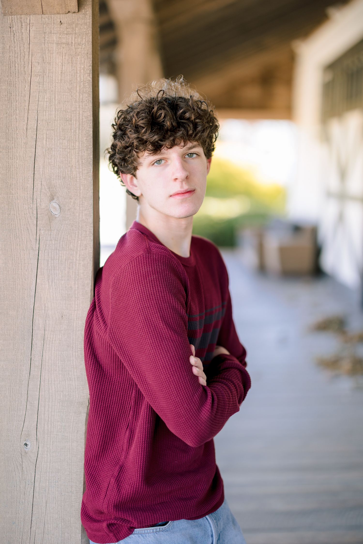 Person in burgundy sweater poses against light colored wall in casual portrait series in Summerfield NC  with a Family Photographer