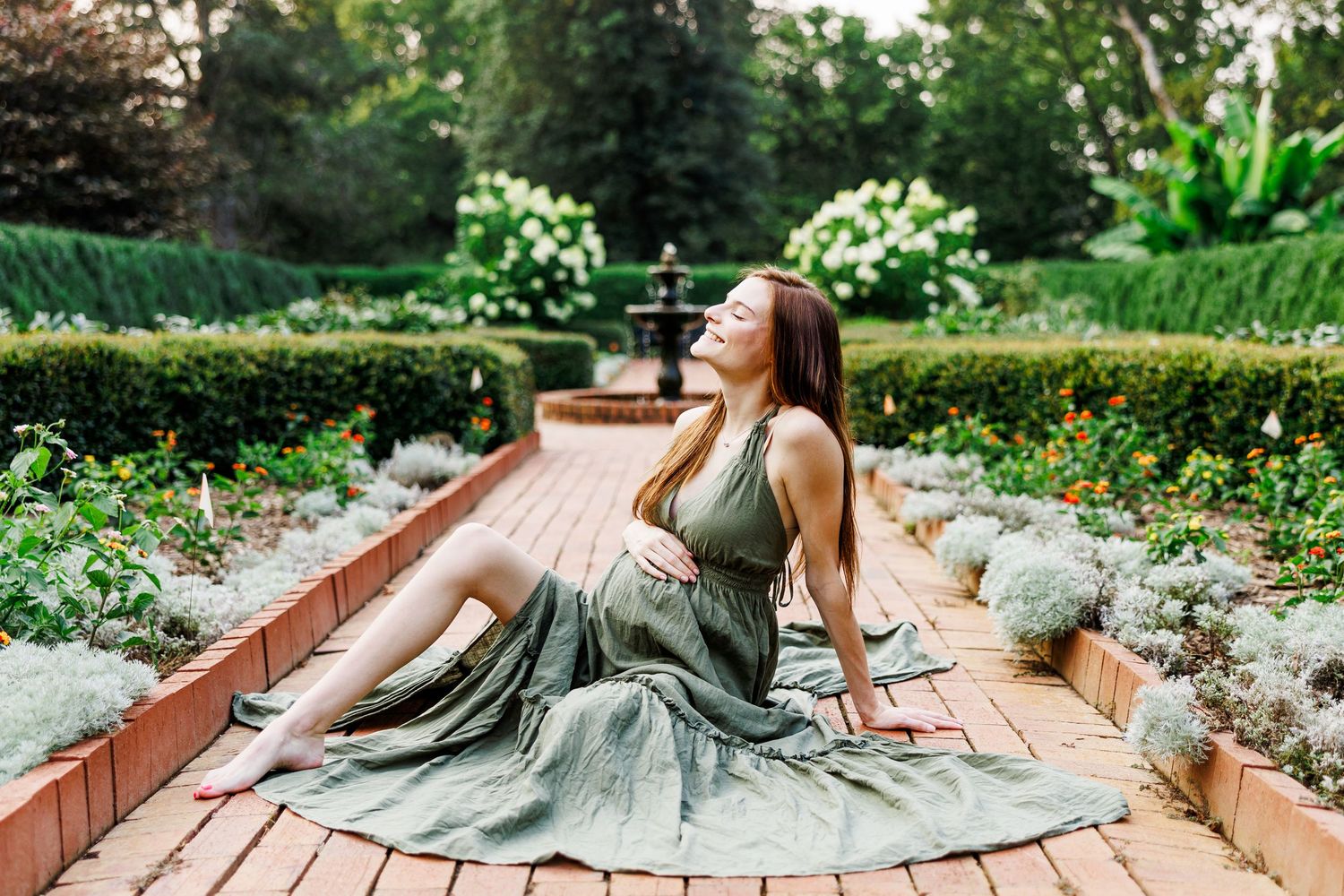 A flowing grey dress spreads across wooden deck boards in an artistic outdoor portrait in Clemmons NC  with a Maternity Photographer
