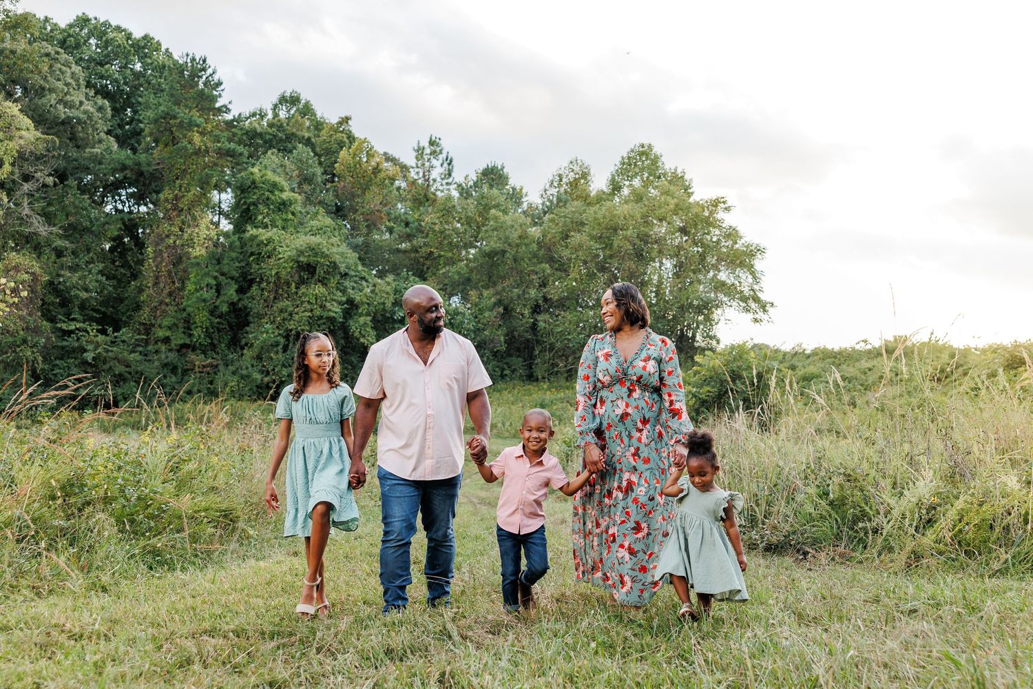 Family enjoying time together walking through a sunny meadow in Greensboro NC  with a Family Photographer