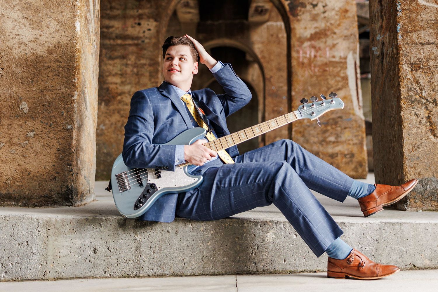 Person in blue suit playing electric guitar while sitting on stone steps  for Senior Portrait Session in Winston Salem