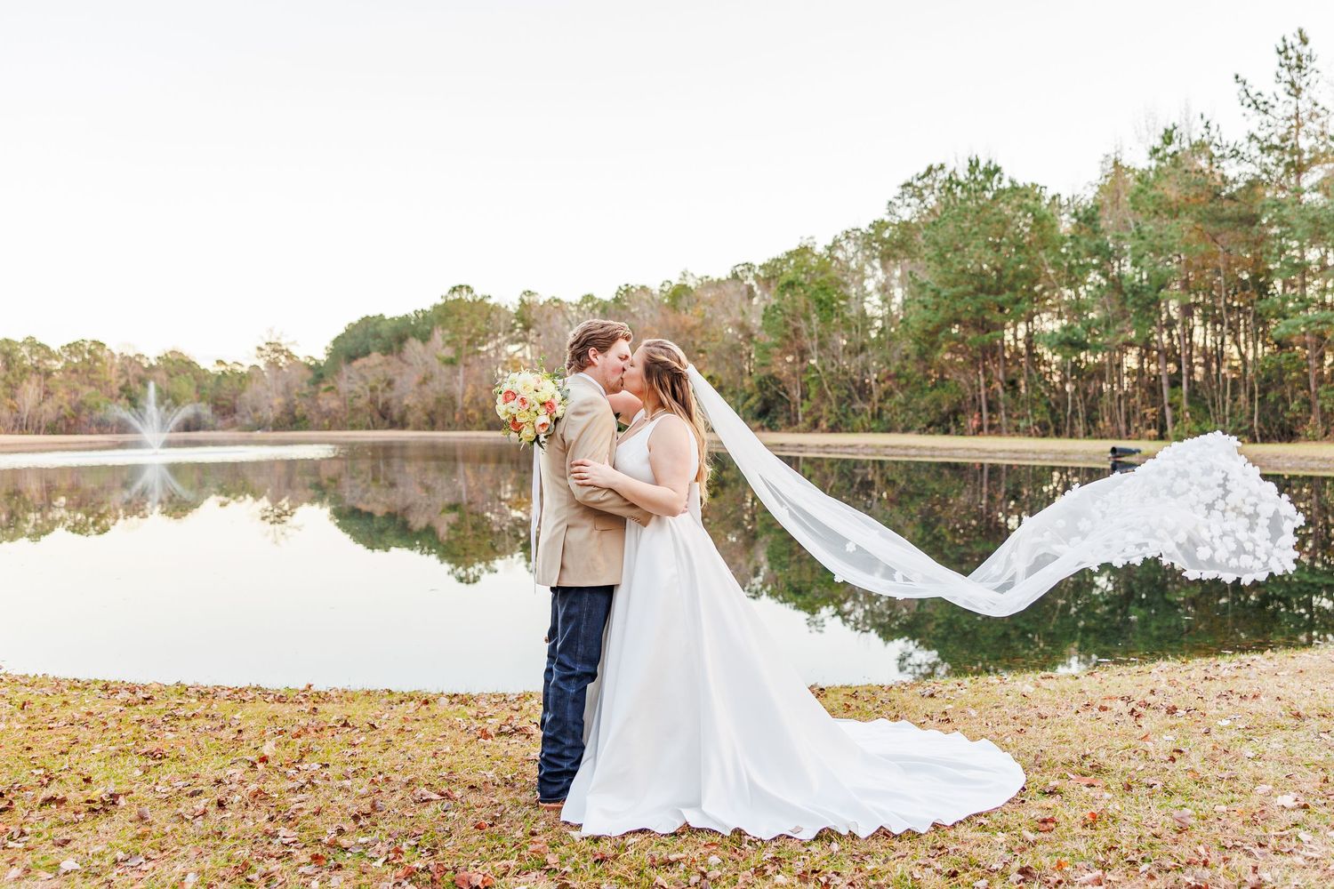 Wedding couple posing in a field with flowing veil during golden hour  with NC Wedding Photographer
