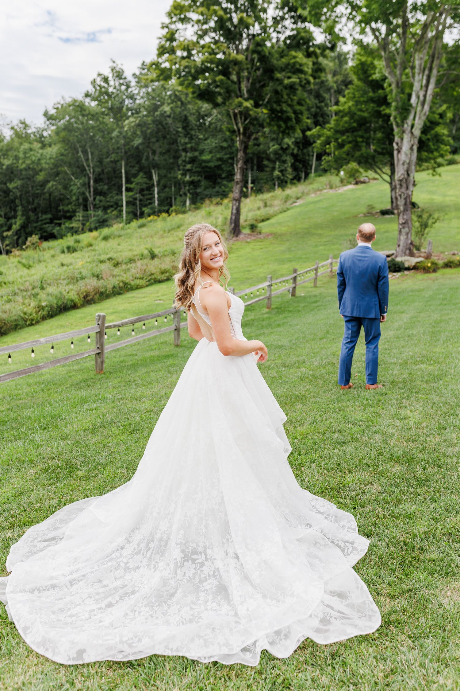 Flowing white wedding dress train spread across green hillside during outdoor photo session at Appalachian View Venue with Boone
