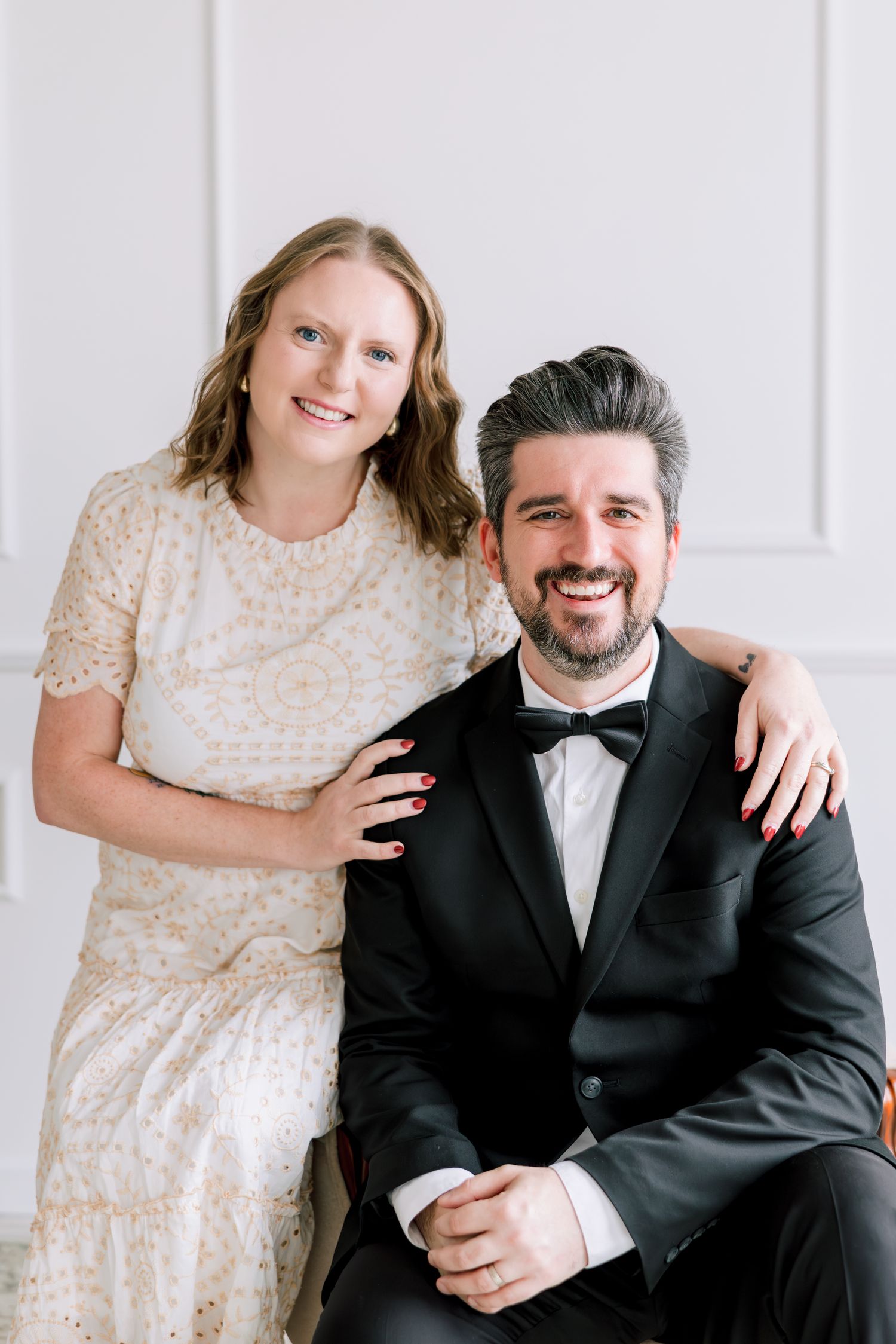 Formal portrait session featuring classic black tie attire against white backdrop.