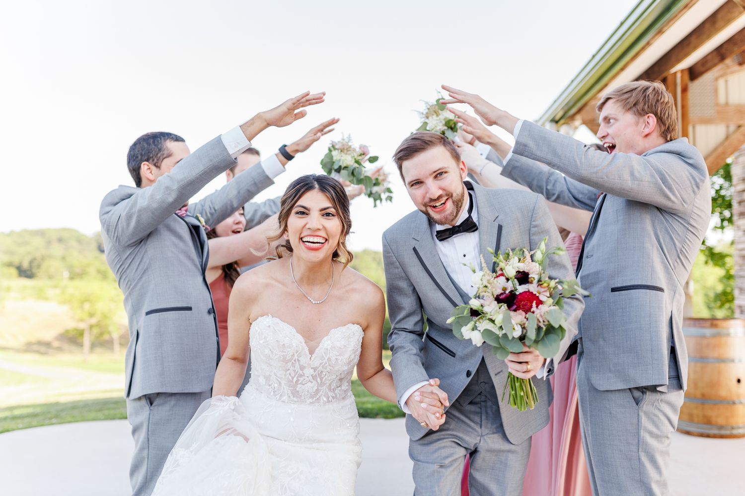 Wedding party in gray suits and white dresses posing joyfully outdoors  with NC Wedding Photographer