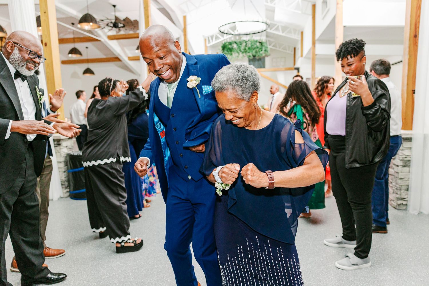 A joyful dance celebration at a wedding reception with guests looking on.