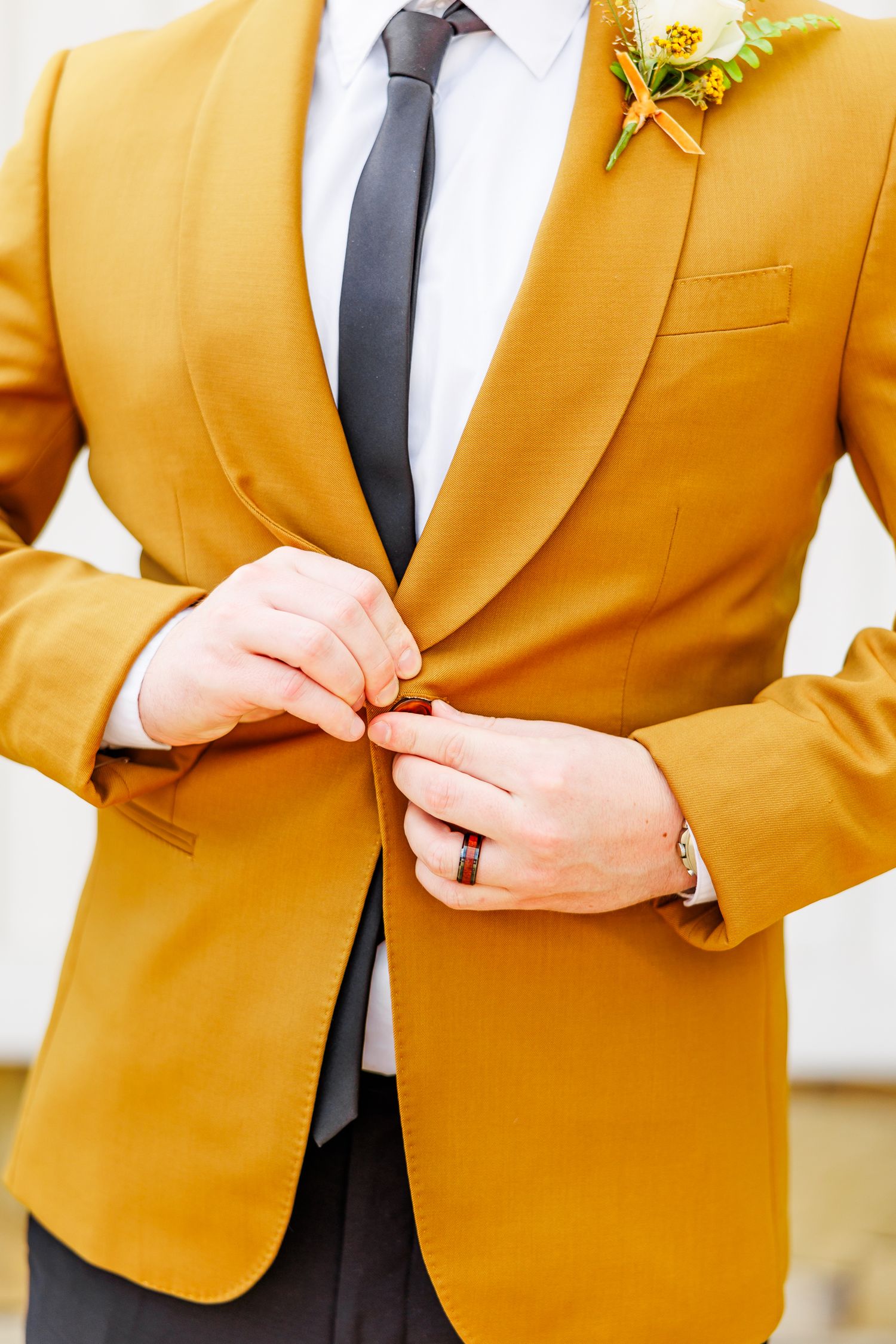 Close-up details of mustard yellow suit jacket with boutonniere.