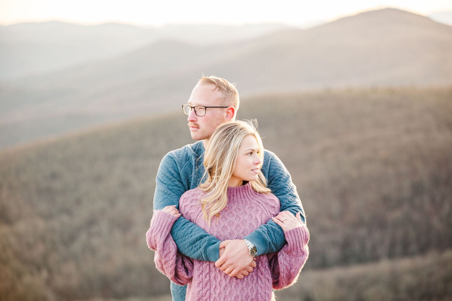 Couple embracing on mountain peak with dramatic sunset and valley views Boone NC Engagement Photographer on the Blue Ridge Parkway