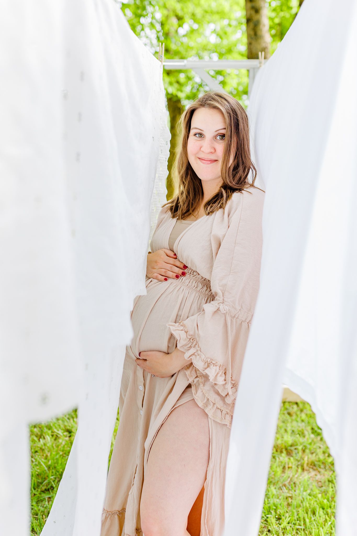 Maternity photo shoot in a dreamy outdoor setting with white flowing curtains and soft pink dress in NC  with a Maternity Photographer