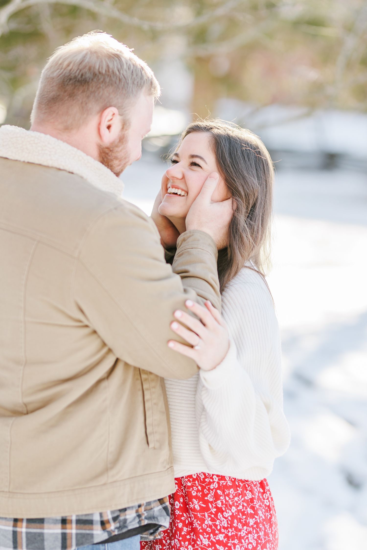 Winter engagement photos in snowy setting with red dress and tan jacket with Winston Salem Engagement Photographer