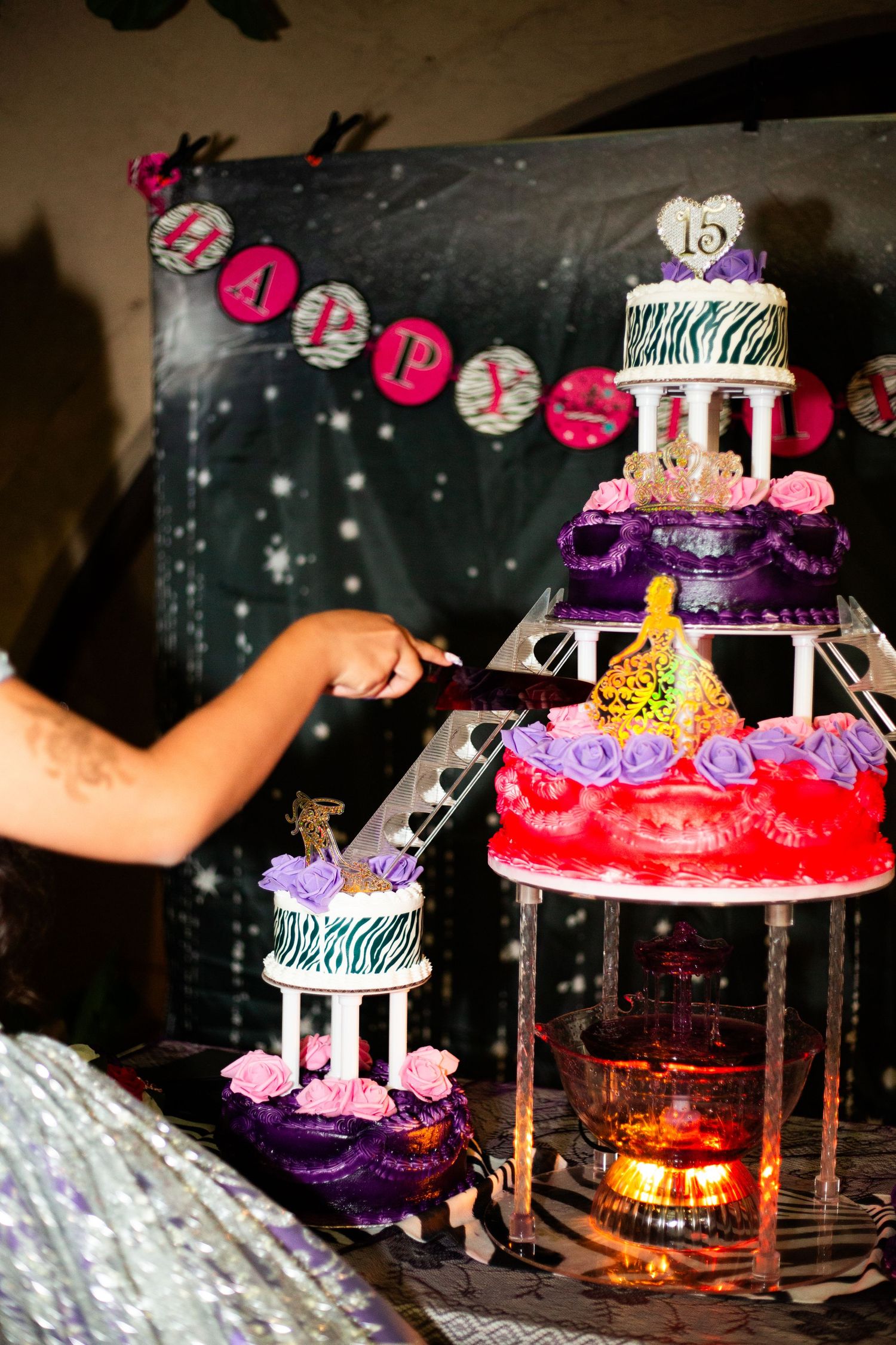 Elegant quinceañera birthday cake display with purple and red tiers, zebra print, and a number 15 topper.