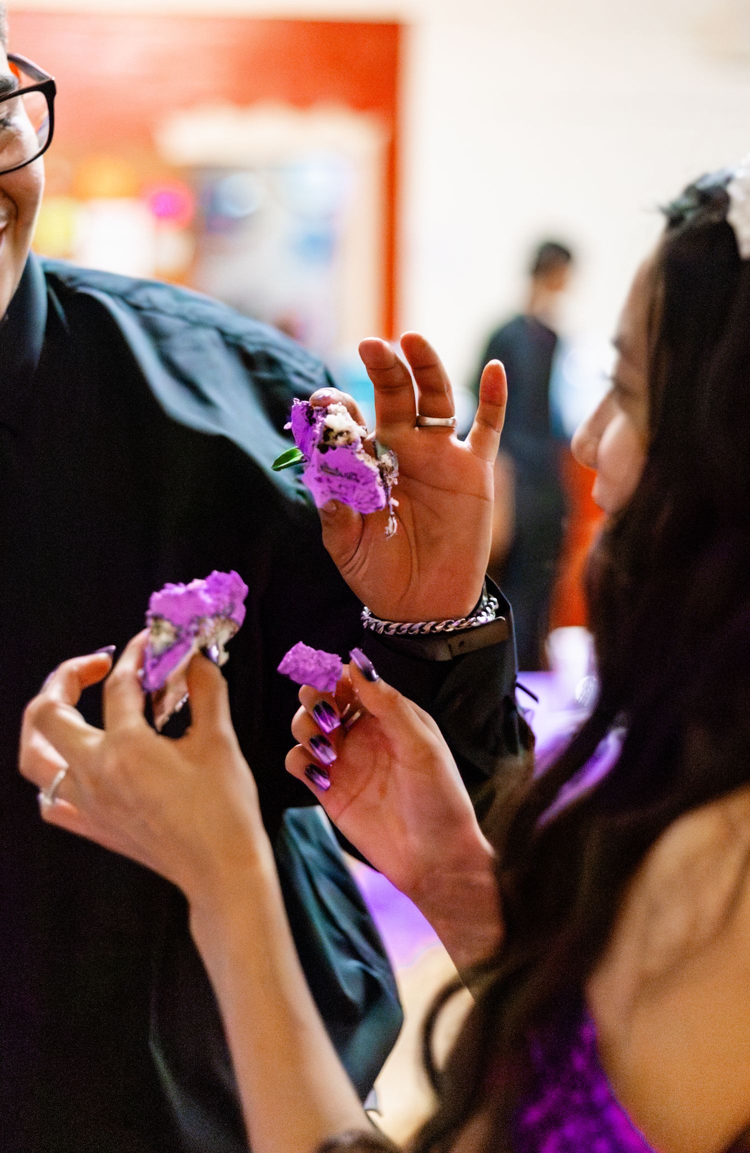 A young woman pins a purple corsage on a person's wrist at a formal event, wearing a purple dress.