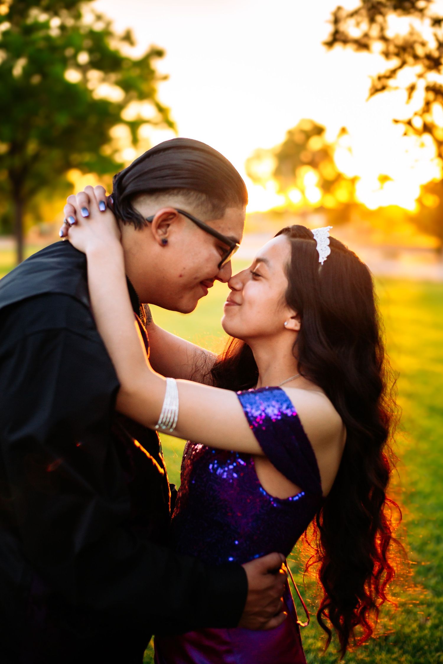 Couple sharing a romantic moment at golden hour sunset in a park, woman in purple sequin dress.