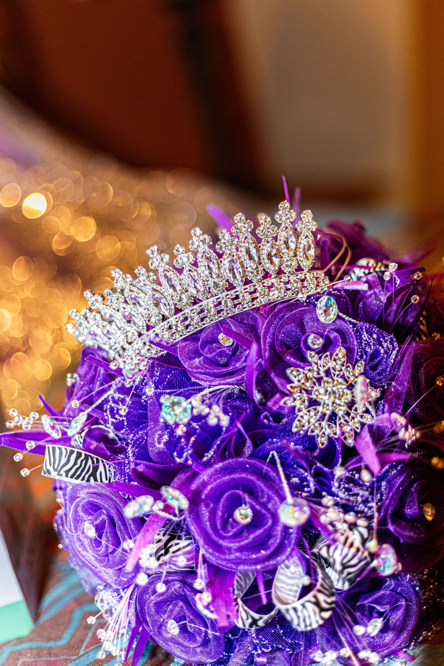 Purple quinceañera bouquet adorned with crystal tiara and rhinestone brooches on purple roses.