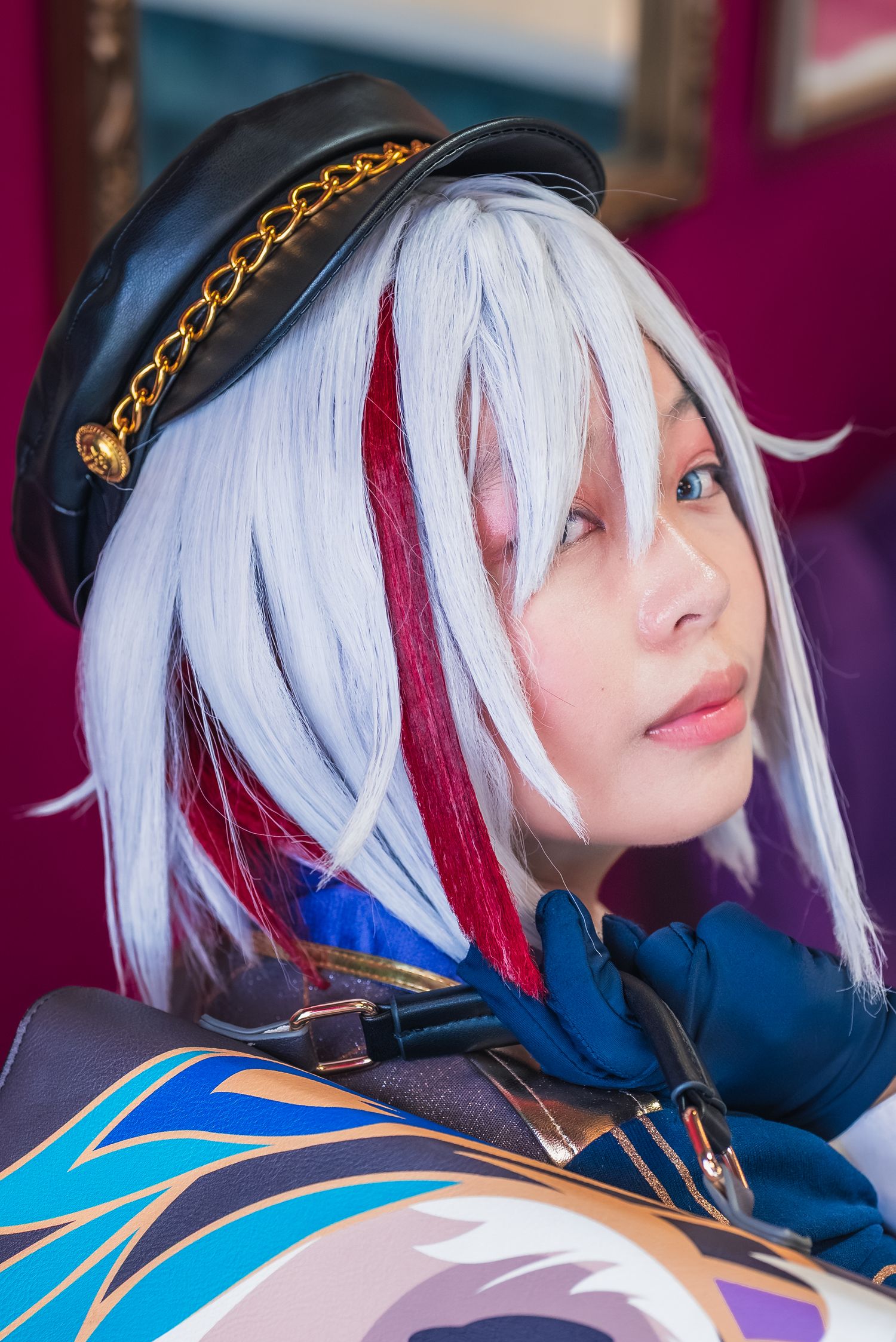 Up-close headshot of a cosplayer looking over their right shoulder, dressed as Topaz from Honkai: Star Rail.
