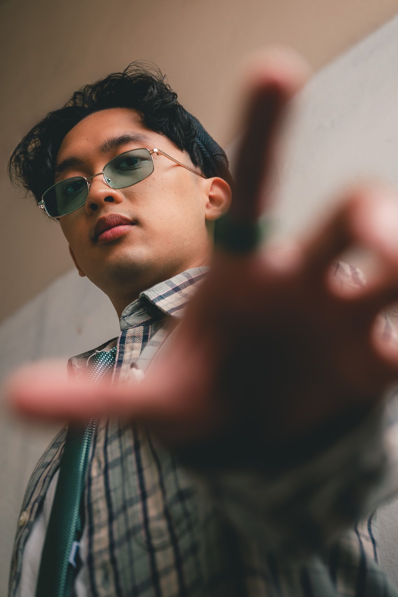 Portrait of a man in business casual extending his right hand downward to the camera as if about to grab the lens.