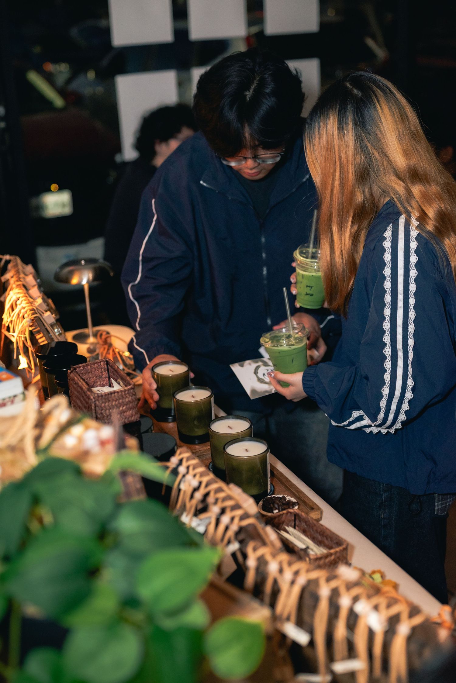 Portrait of 2 customers interacting with the candles and scent diffusers at the popup display.