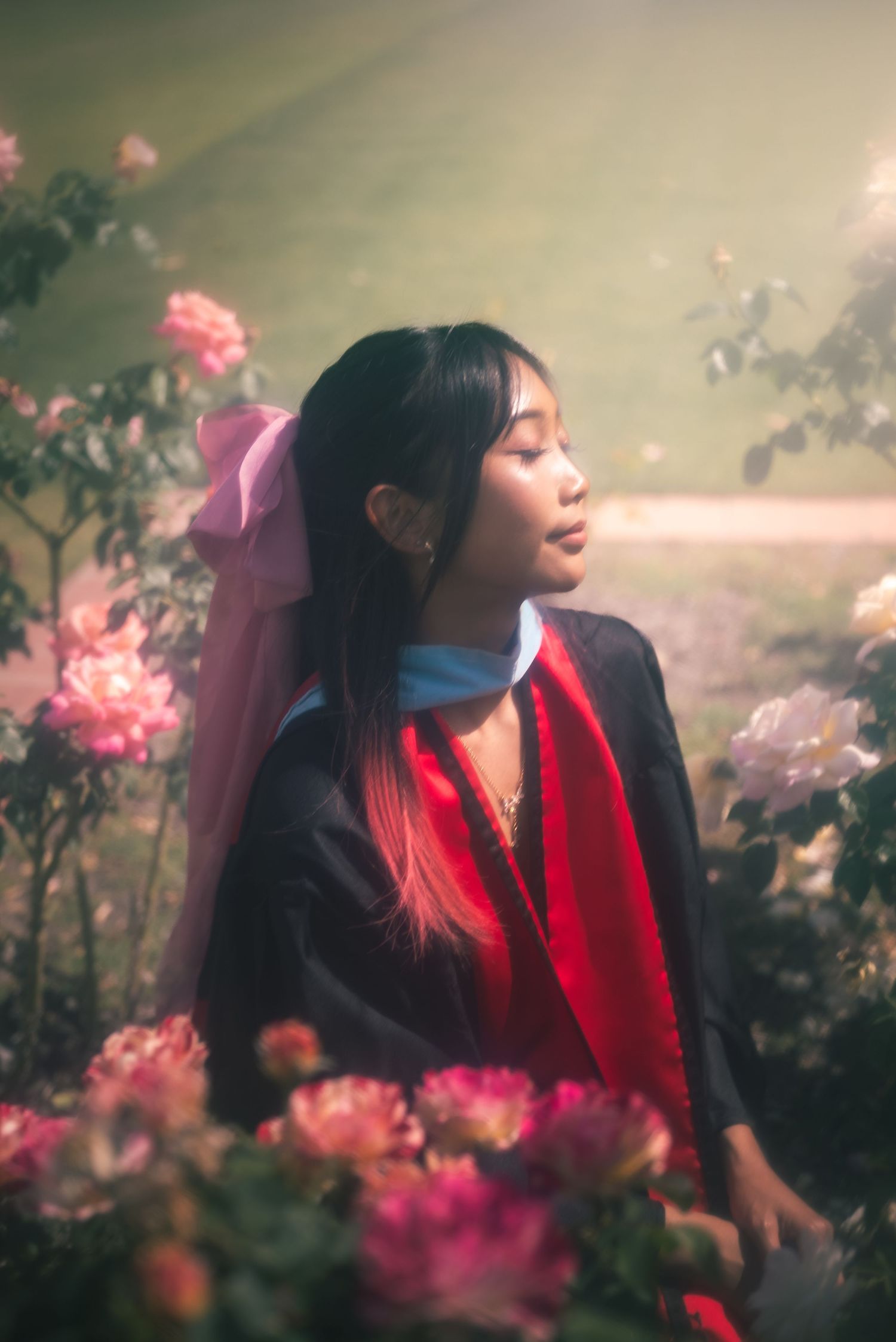 Portrait of a woman sunbathing and surrounded by roses in celebration of her graduation.