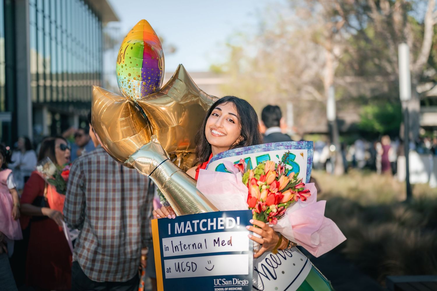 Portrait of a woman smiling gleefully and clutching several gifts in celebration of her matching into residency.