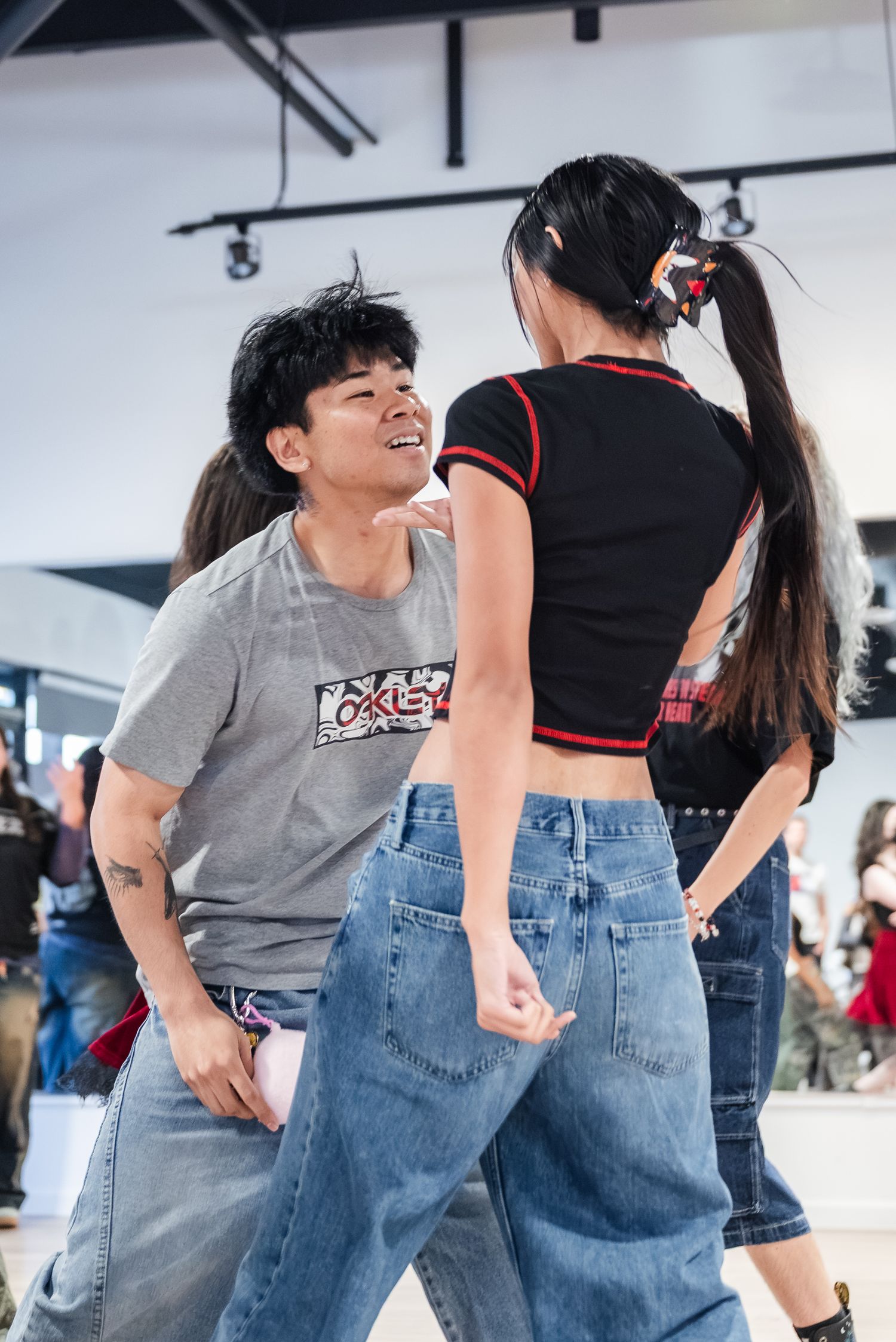 Portrait of a man and woman dancing closely together amongst others in a crowd as the woman beckons the man towards her.