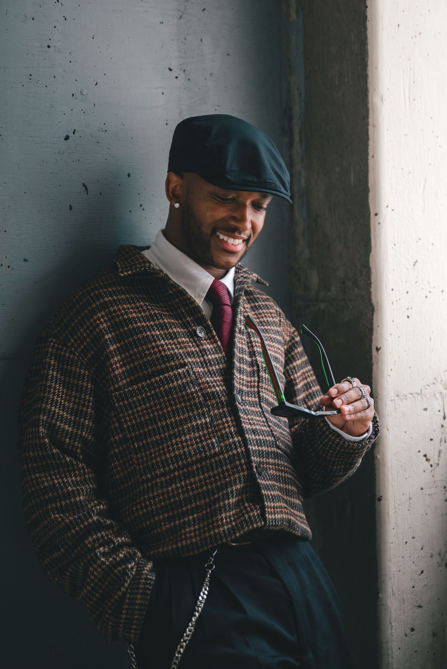 Portrait of a man in business-casual fashion staring down at his sunglasses and smiling.