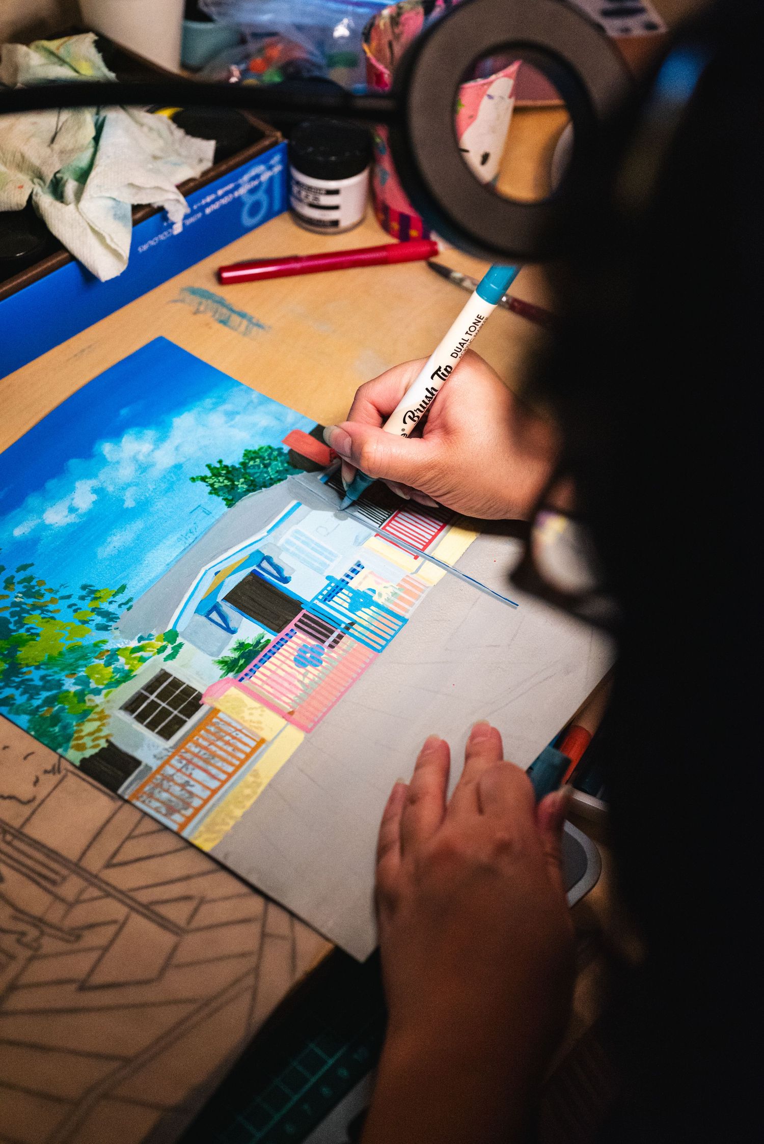 Over-the-shoulder behind the scenes shot of a woman adding detail work to her painting.