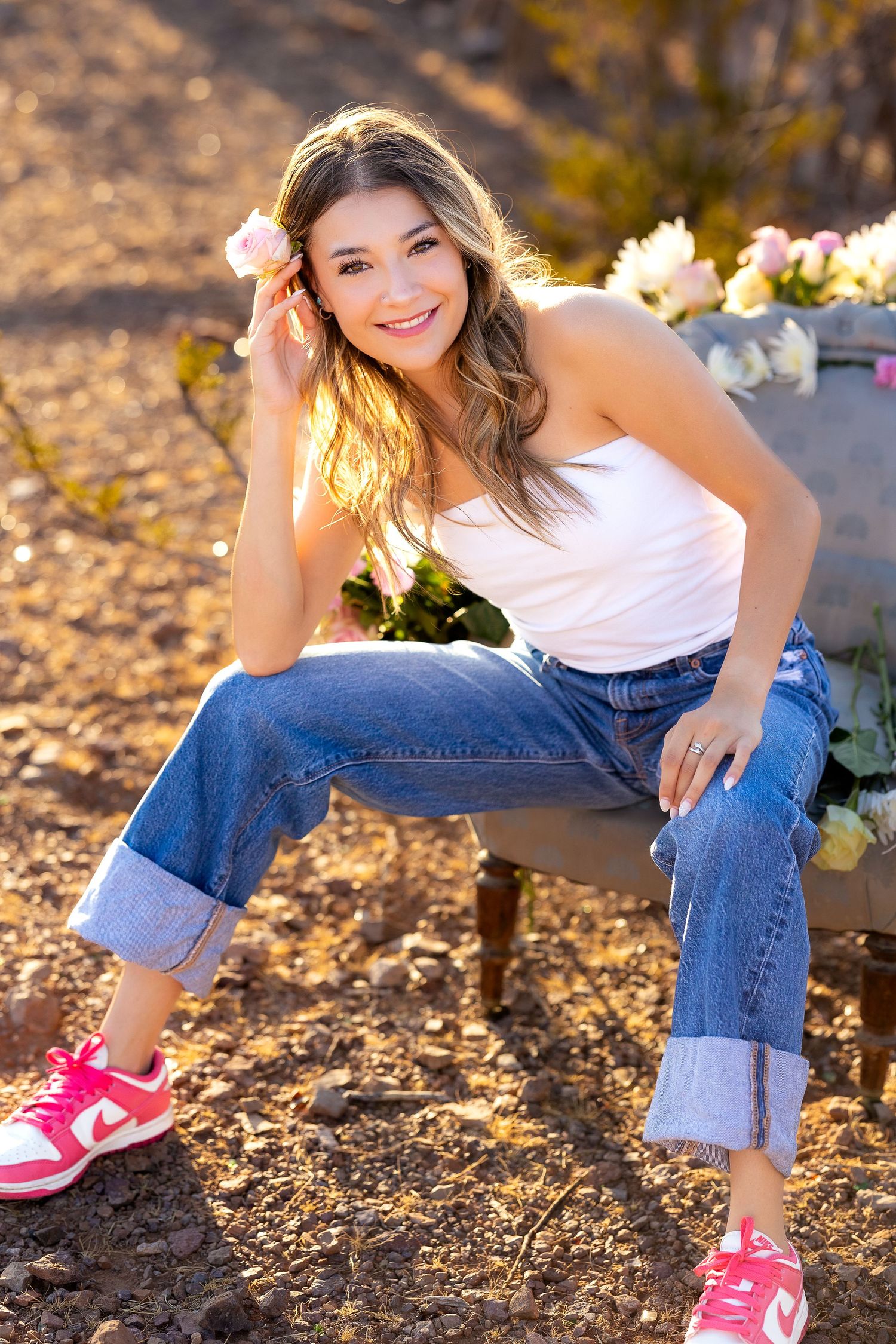 High School senior during senior portraits sitting in a chair with a flower on her hair. Chair is decorated with flowers.