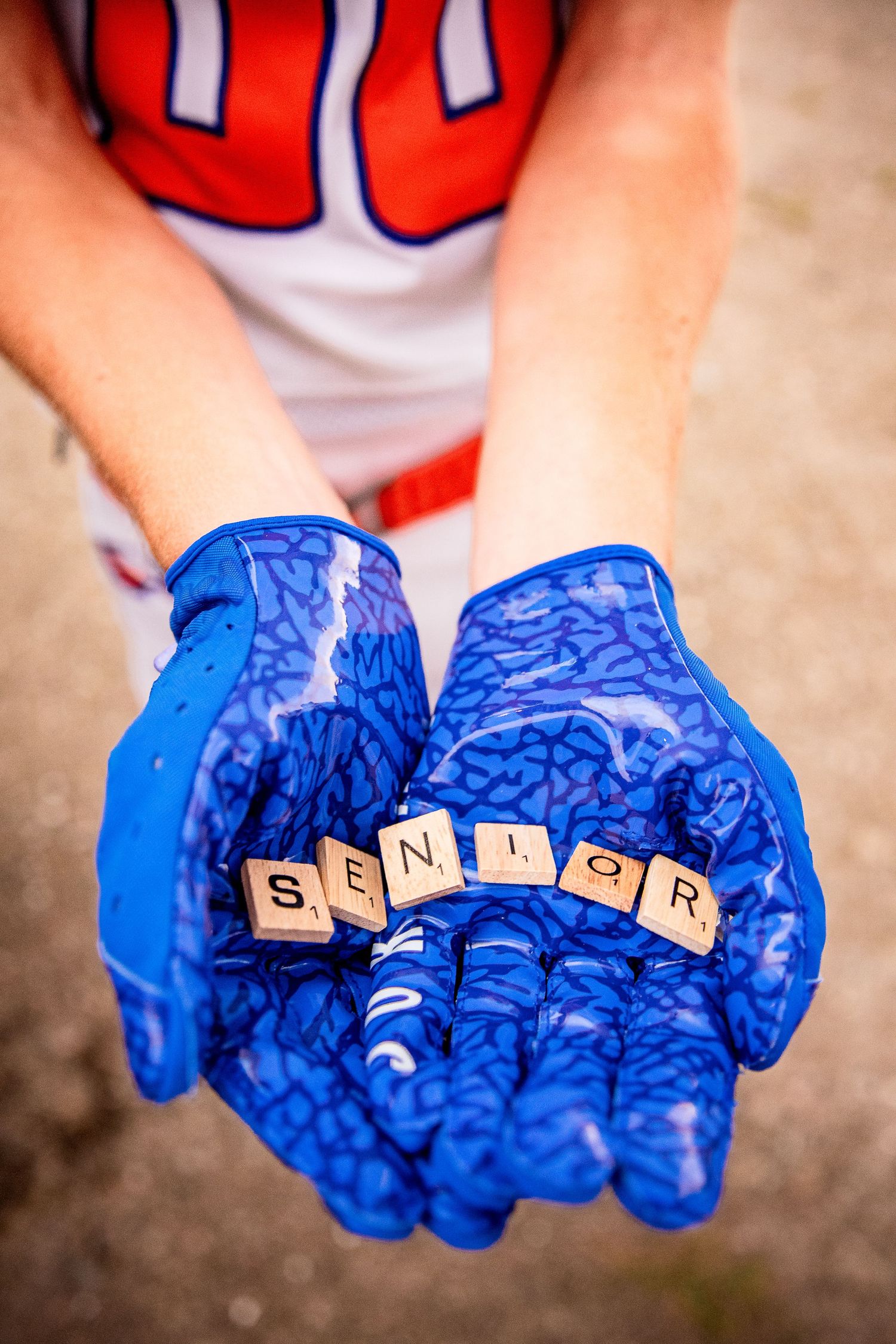 high school Senior football player during his senior pictures.  Image is a closeup of gloves with scrabble tiles spelling SENIOR.