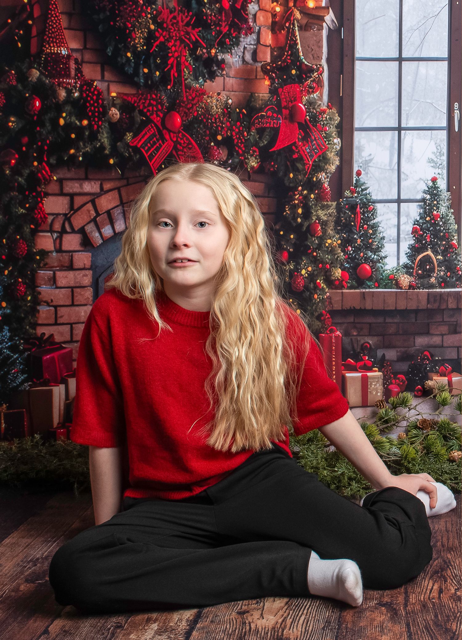 Girl in red shirt posing against Christmas decorated brick wall background.