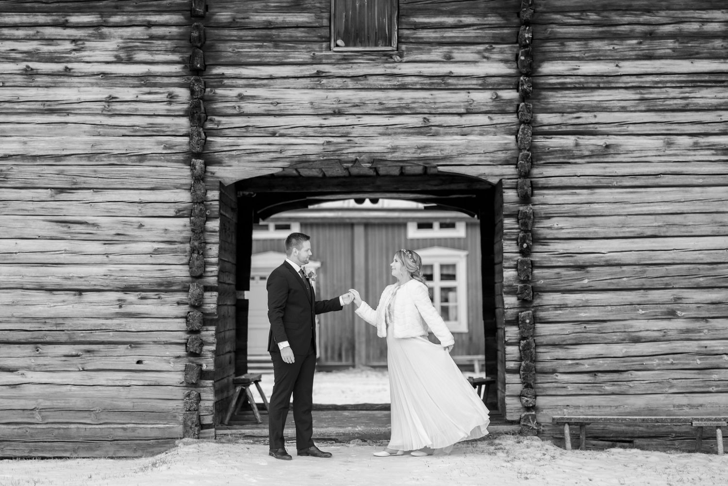 Rustic winter wedding photos against weathered wooden barn wall in snowy setting.