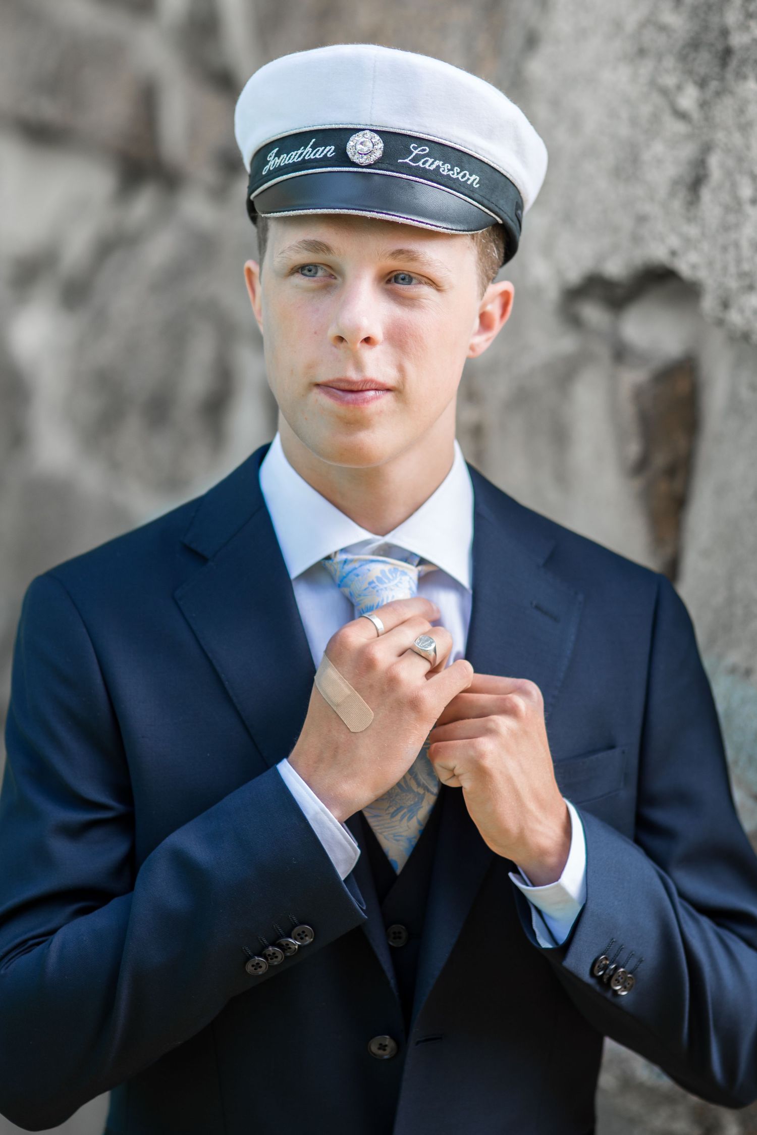 Side profile portrait showing graduation attire against concrete background.
