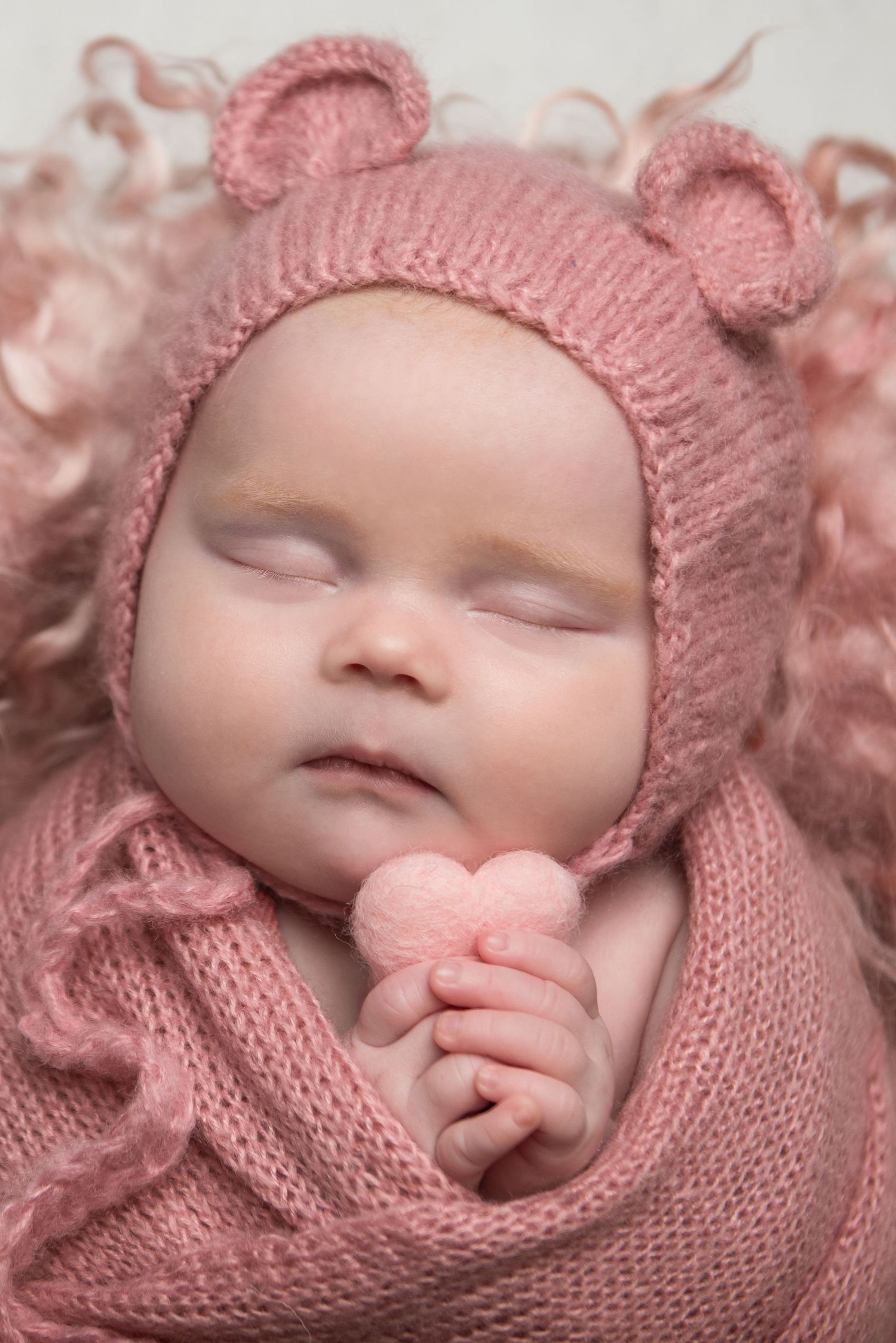 Sweet newborn portrait in soft pink knit bear bonnet and matching wrap.