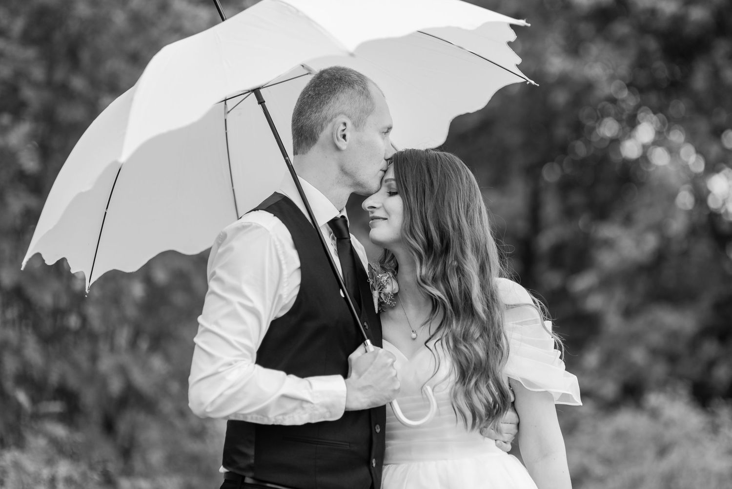 Black and white wedding portraits featuring a white umbrella as a prop.
