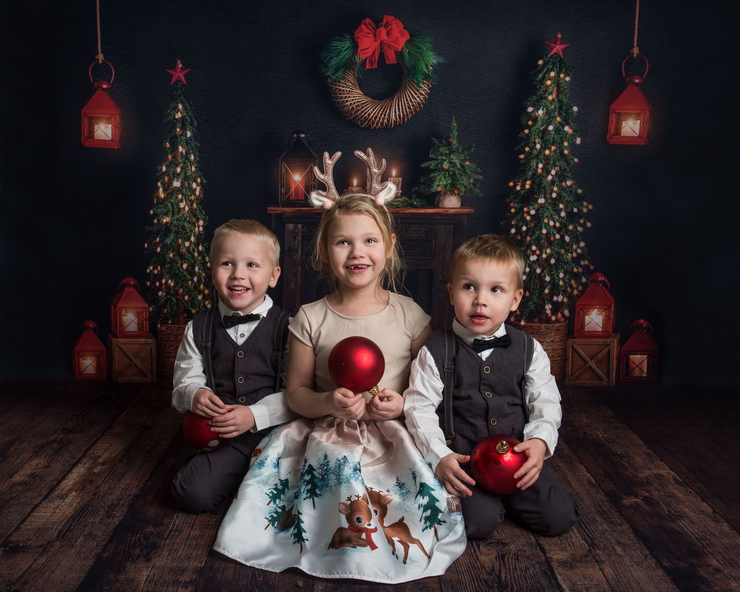 Holiday photo scene with decorated Christmas trees, red bows, and vintage lanterns on wooden flooring.