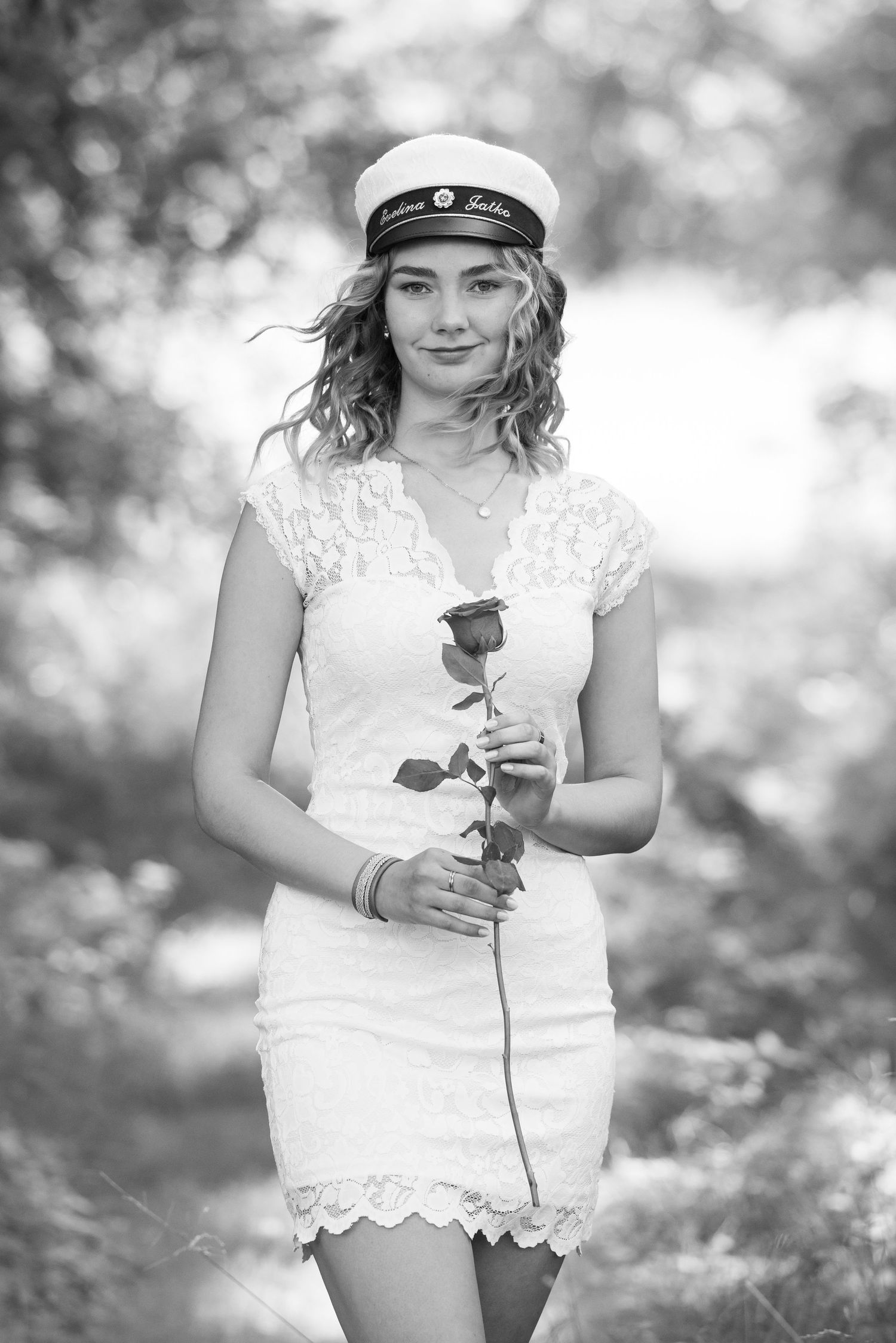 Black and white portrait holding a rose in a garden setting.