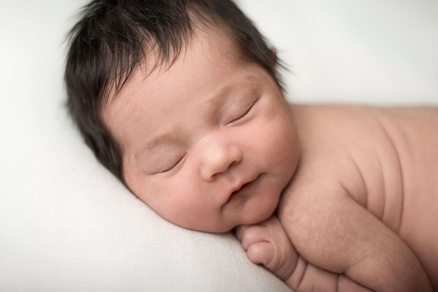Serene newborn photography series with clean white background and natural poses.