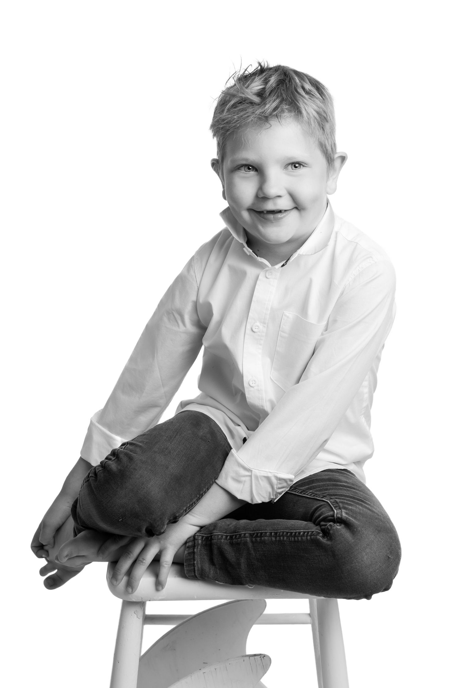 Black and white portrait series of child in white shirt sitting casually on stool.