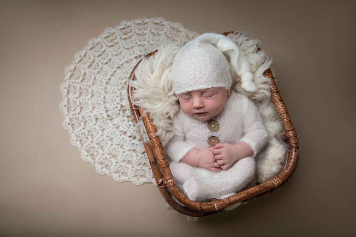 Artistic newborn portrait with soft brown tones and delicate white wrapping.