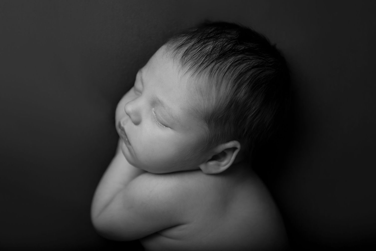 Black and white portrait series showing close-up profile views of a sleeping newborn.
