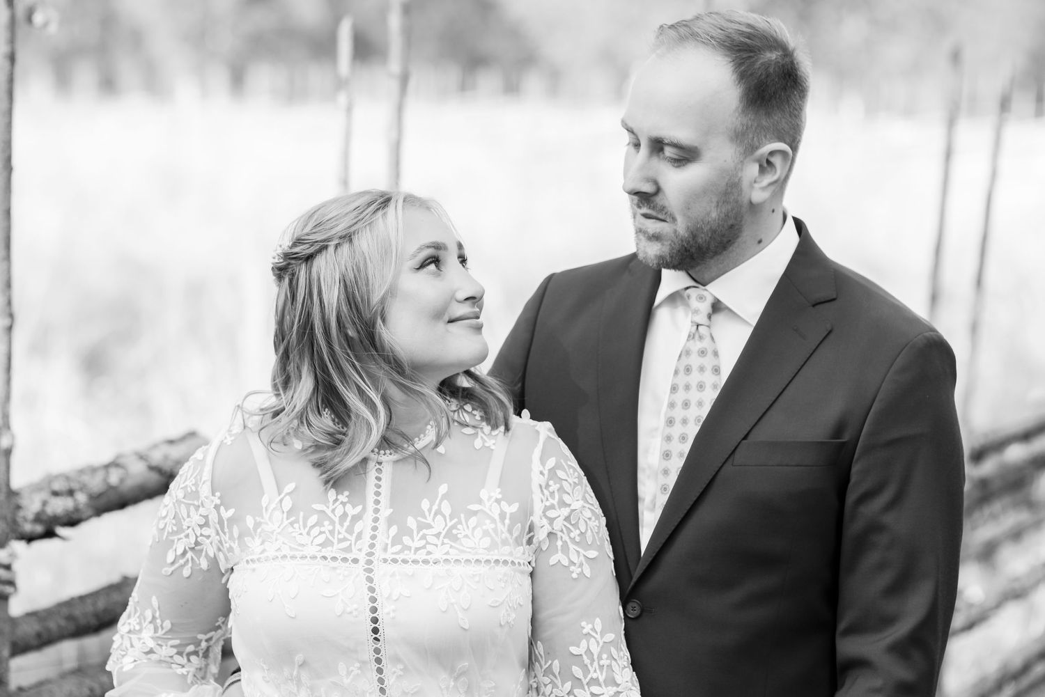 Romantic black and white photo of couple in wedding attire sharing intimate moment outdoors.