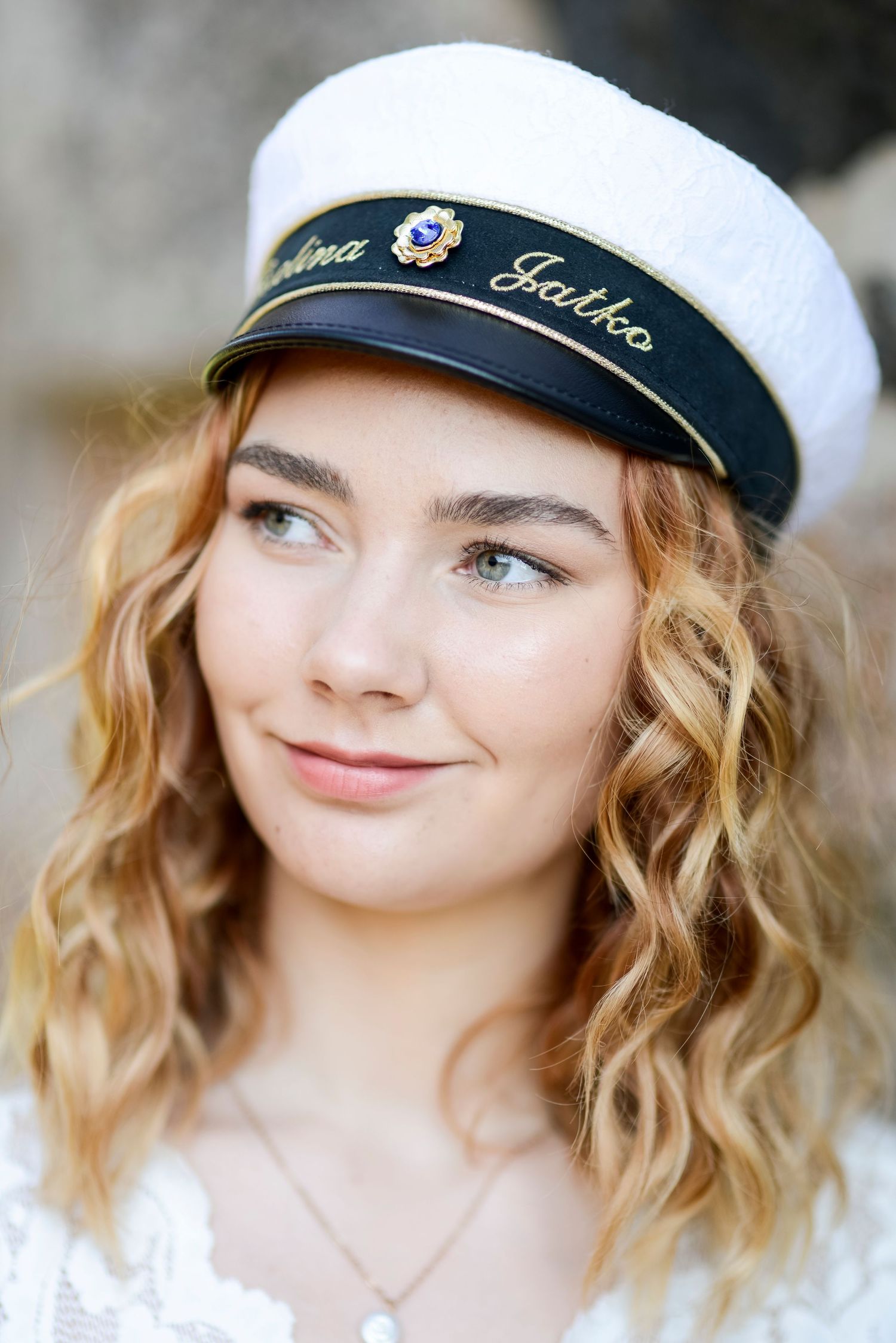 Smiling portrait in a navy sailor cap with embroidered details.