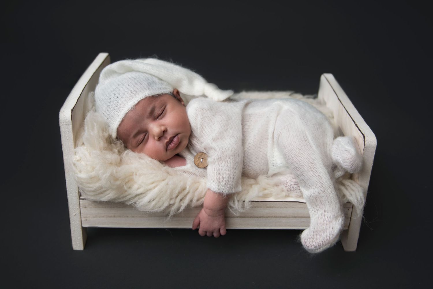 Artistic black and white series of sleeping newborn on white platform.
