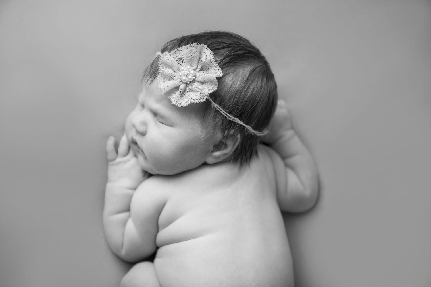 Svart vitt artistisk nyfödd fotografi serie som visar en fridfullt sovande baby i en mjuk pose..