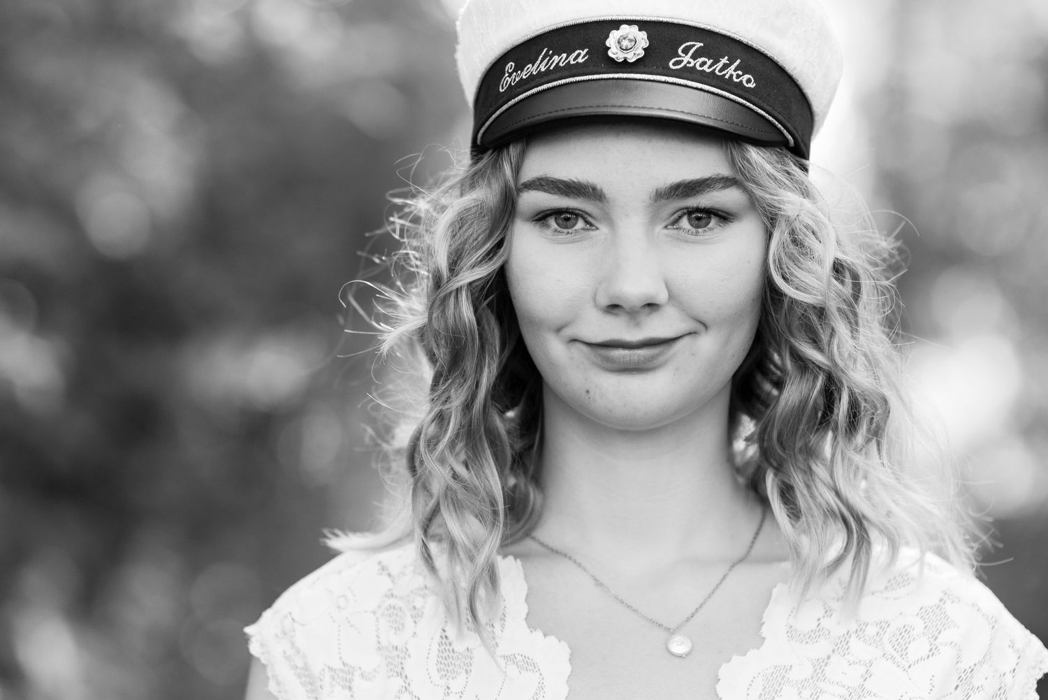 Black and white portrait series wearing white sailor cap with decorative trim.