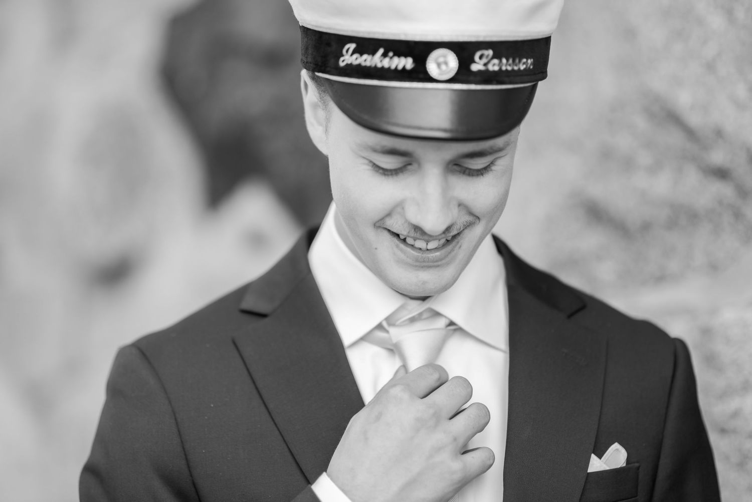 Black and white portrait adjusting tie in formal attire.