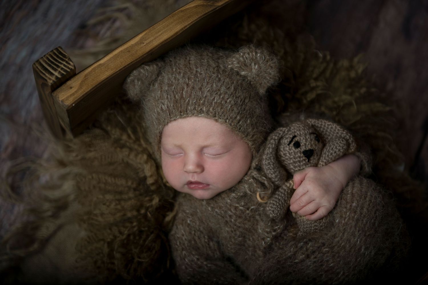 Moody newborn portrait series with rustic wood textures and vintage styling elements.