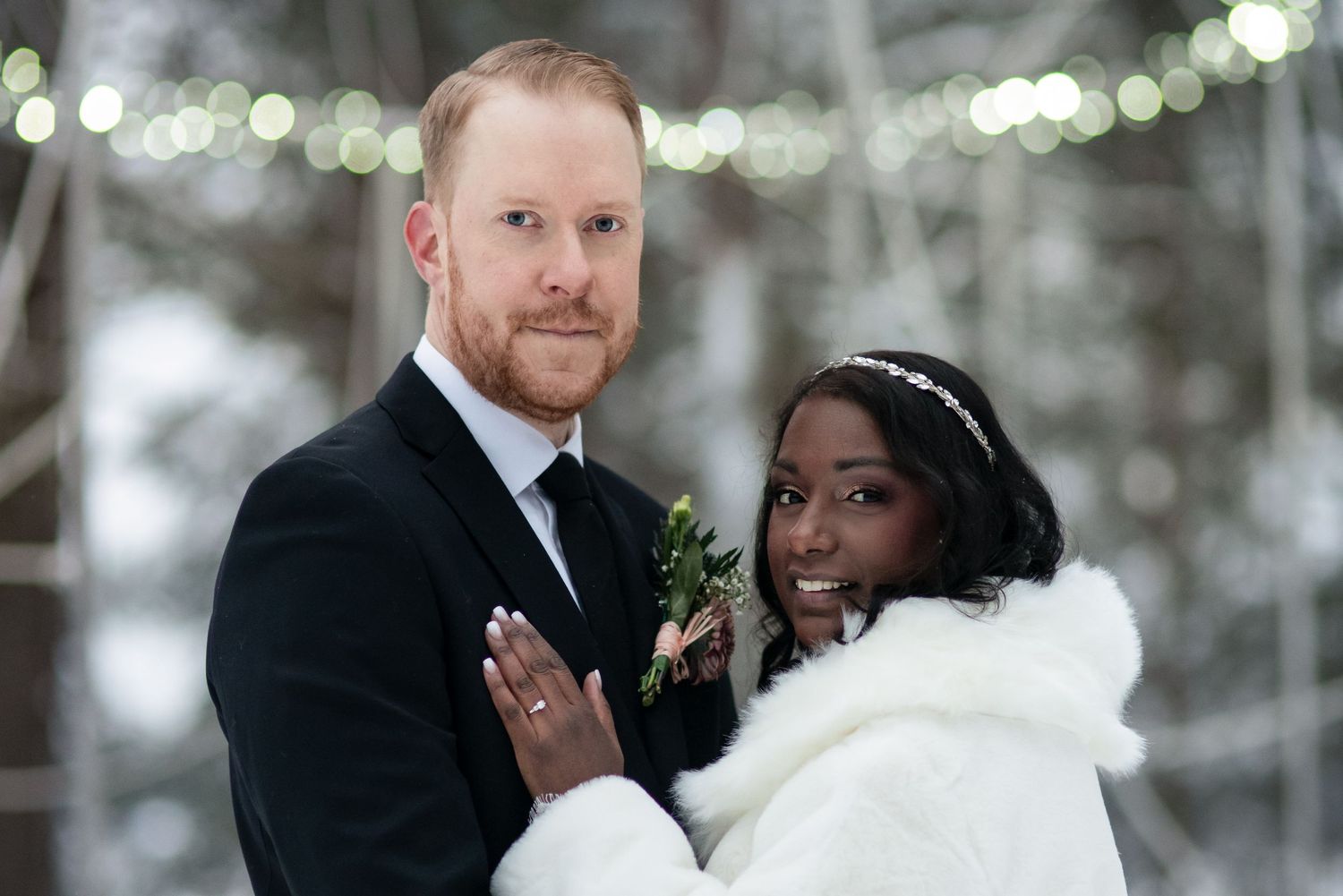 A tender wedding moment captured in a winter forest with twinkling lights overhead.