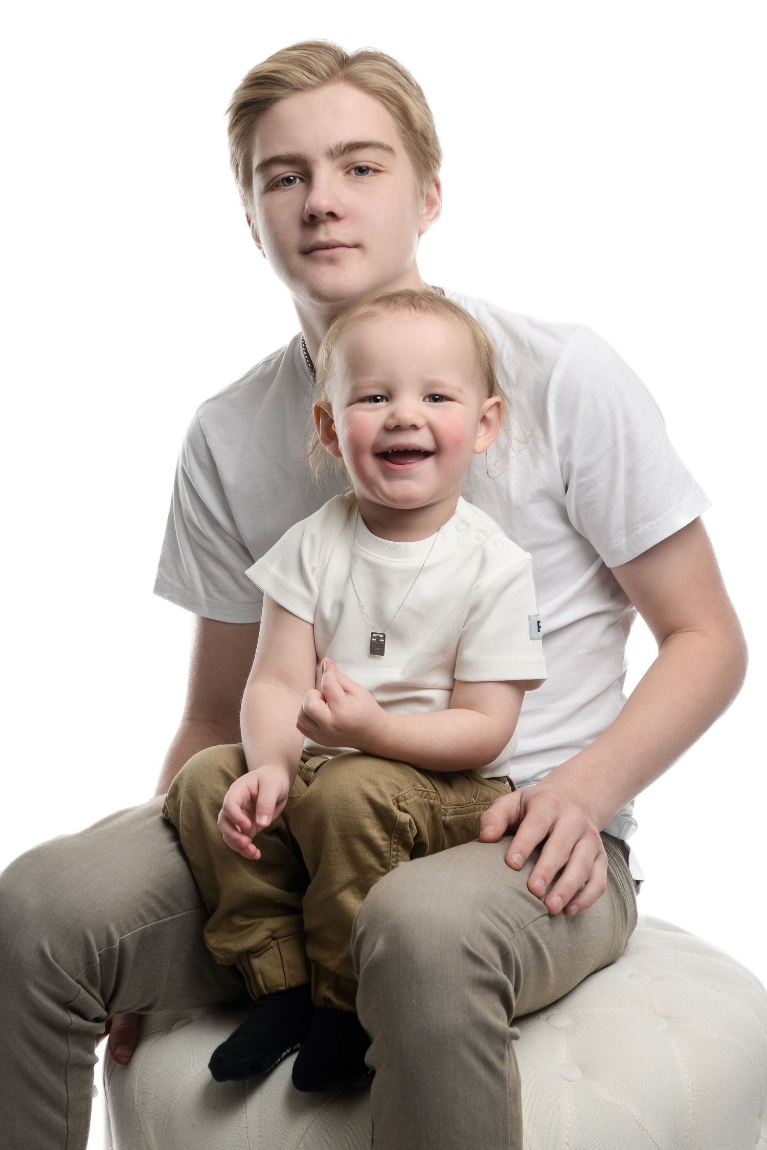 Parent and child in white shirts sitting together on white background.