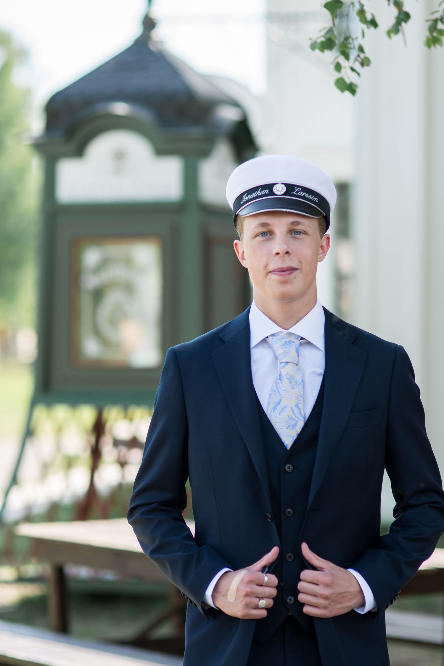 A formal portrait series showing a navy suit and cap against white columns.