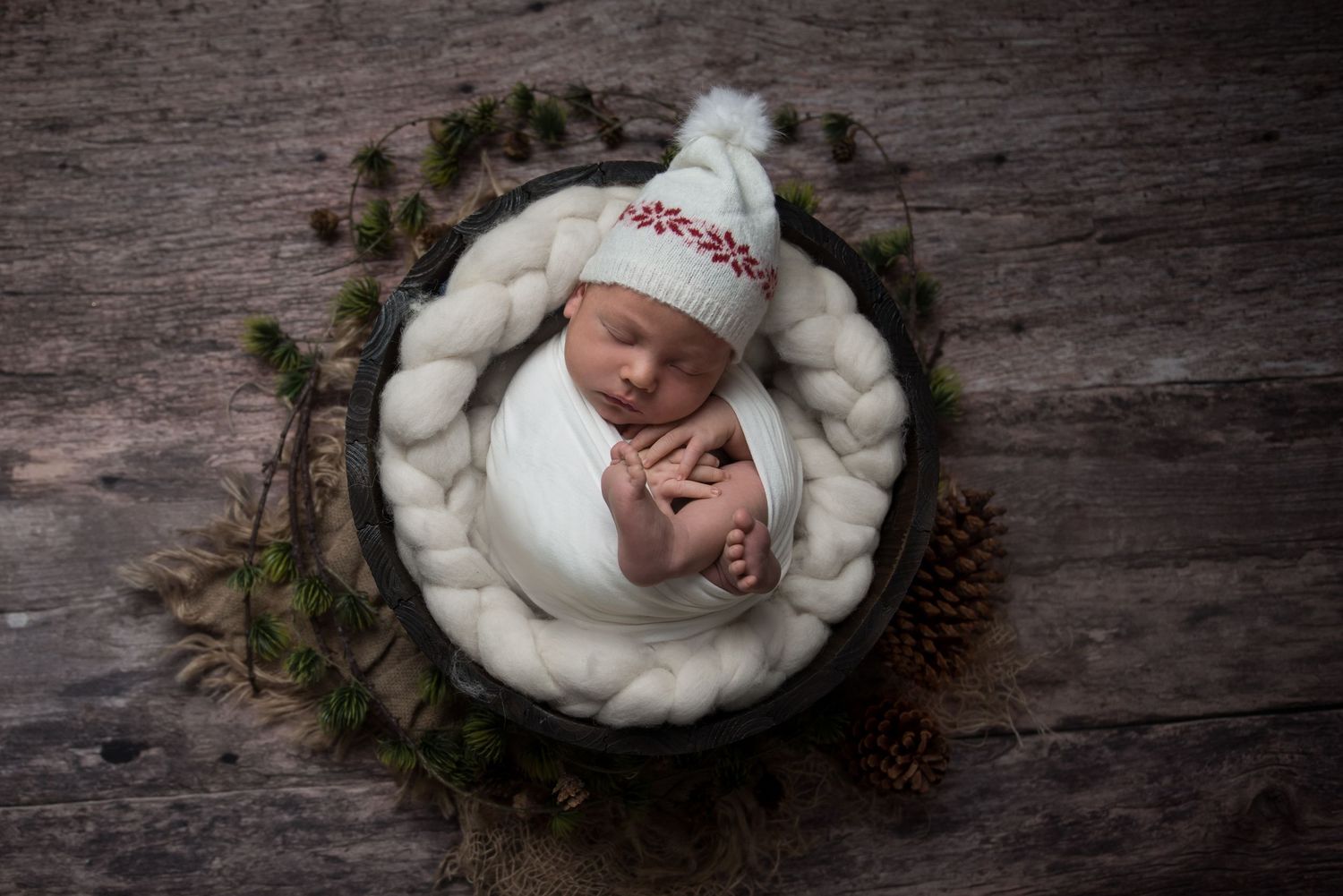 Rustic winter scene with evergreen wreath, pinecones and white textured bedding.